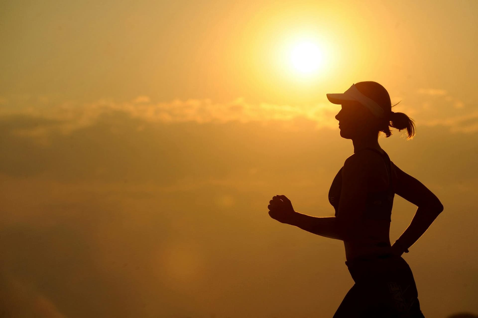 A silhouette of a woman wearing a sun visor