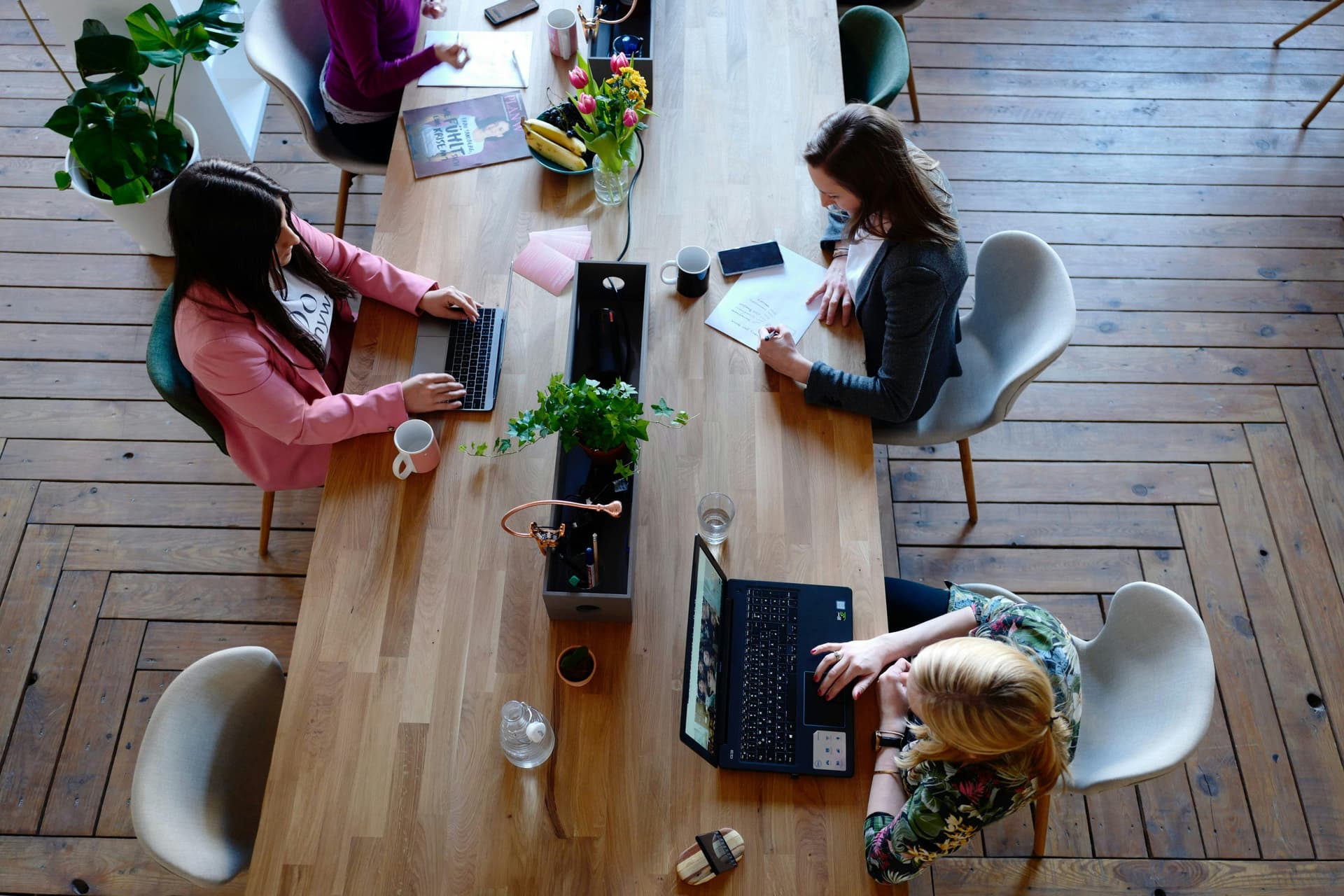 Three women co-working on a long wooden table