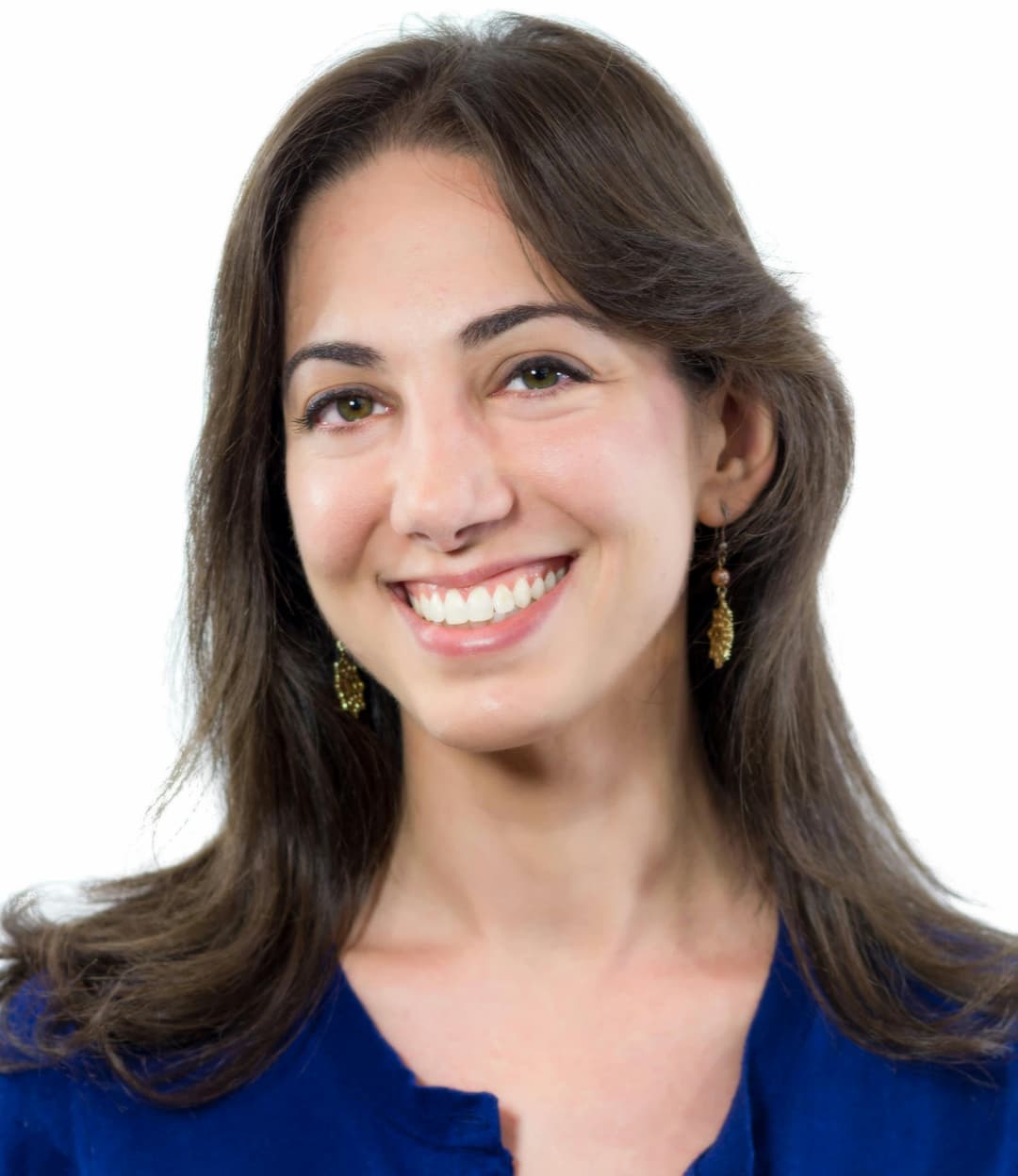 The image shows a smiling woman with shoulder-length dark brown hair. She is wearing earrings shaped like leaves and a blue top. The background is plain white, and she appears to be posing for a professional headshot, looking directly at the camera with a warm, friendly expression.