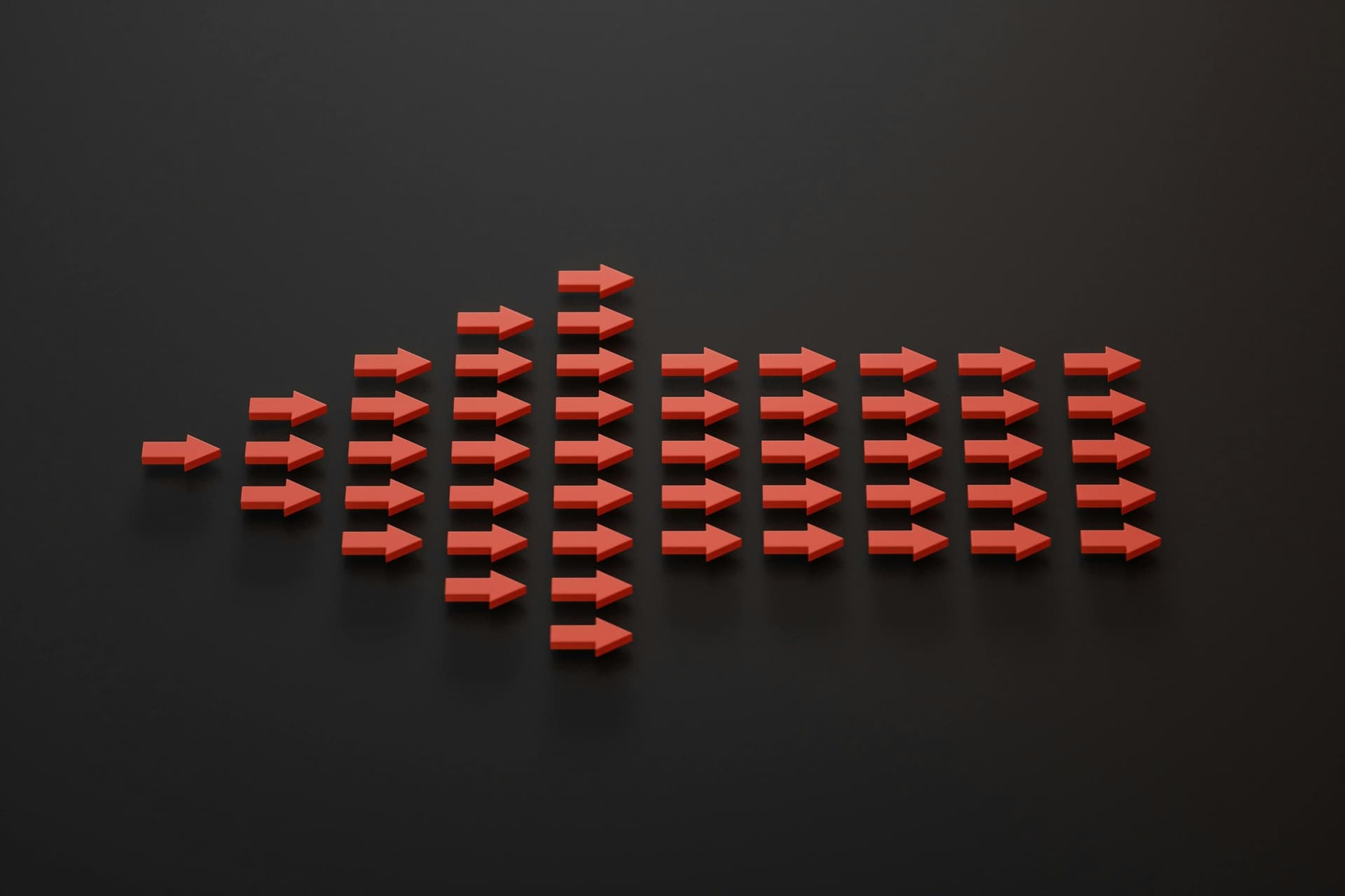Red arrows arranged in a triangle, pointing right, on a black background. The arrows increase in number from left to right, creating a pattern that resembles a bar graph or sound wave.